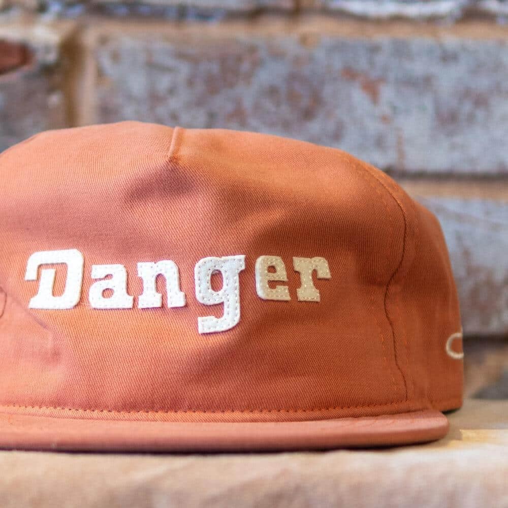 Danger Snapback Hat in burnt orange by the Ampal Creative. Front close-up.